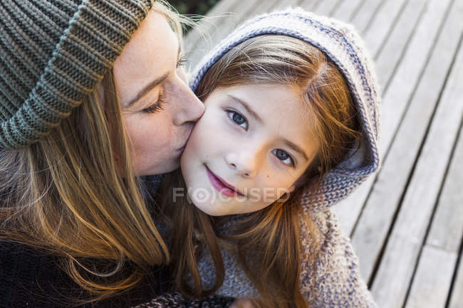 Мати цілує дочку на щоці, портрет високого кута — стокове фото