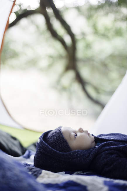 Menino deitado no cobertor, dentro da tenda — Fotografia de Stock