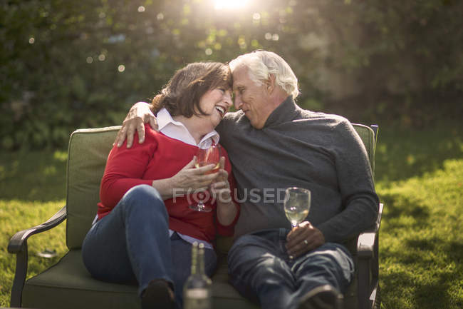 Романтична старша пара сидить обличчям до обличчя на дивані в саду — стокове фото