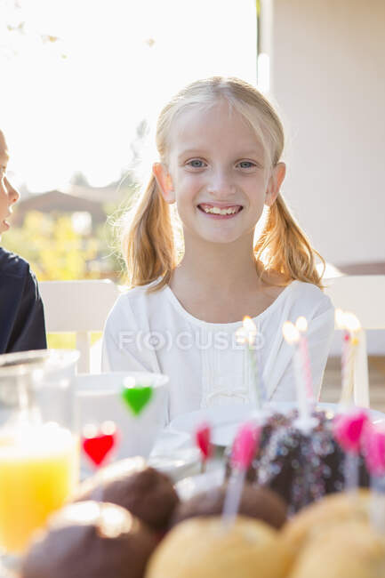 Portrait of happy girl with birthday cake at patio table — Stock Photo