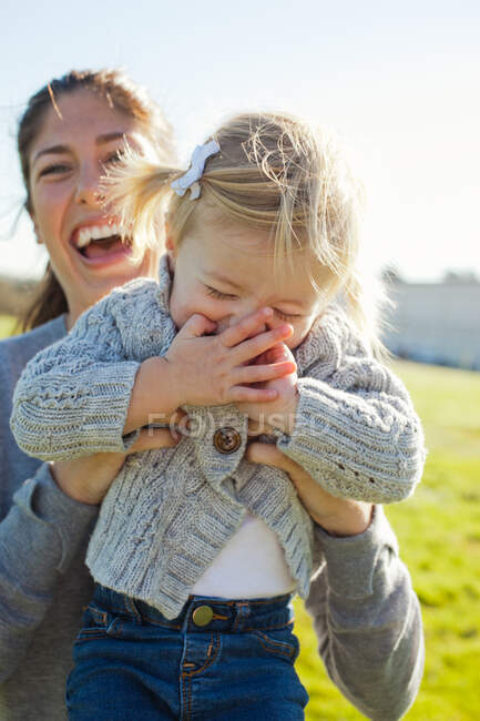 Female toddler being held up by laughing mother — Stock Photo