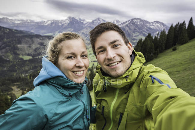 Young hiking couple taking self portrait, on the way down Zinken mountain, Oberjoch, Bavaria, Germany — Stock Photo