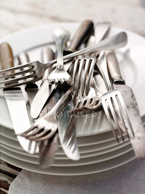Posate accatastate su pila di piatti — Foto stock