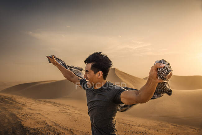 Uomo che tiene la sciarpa nel vento, dune di sabbia Glamis, California, Stati Uniti d'America — Foto stock
