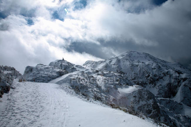 Vista lejana del excursionista en la cima de la montaña nevada - foto de stock