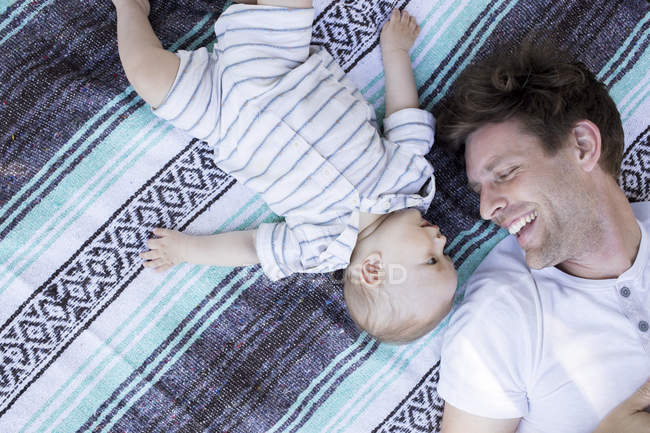 Padre e figlio sdraiati su coperta, faccia a faccia, vista dall'alto — Foto stock