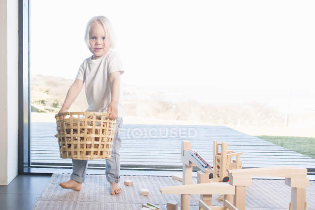 Menino carregando cesta de blocos de madeira — Fotografia de Stock