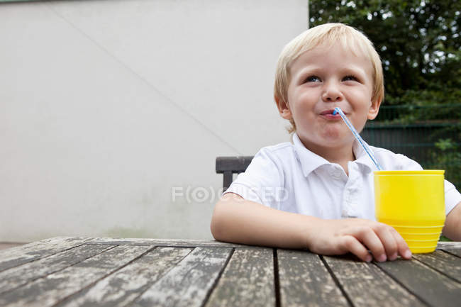 Giovane ragazzo trinking succo con una cannuccia — Foto stock
