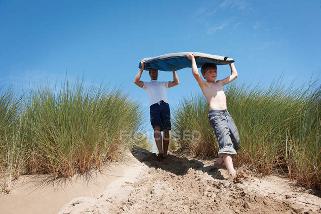 Отец и сын несут доску для серфинга — стоковое фото