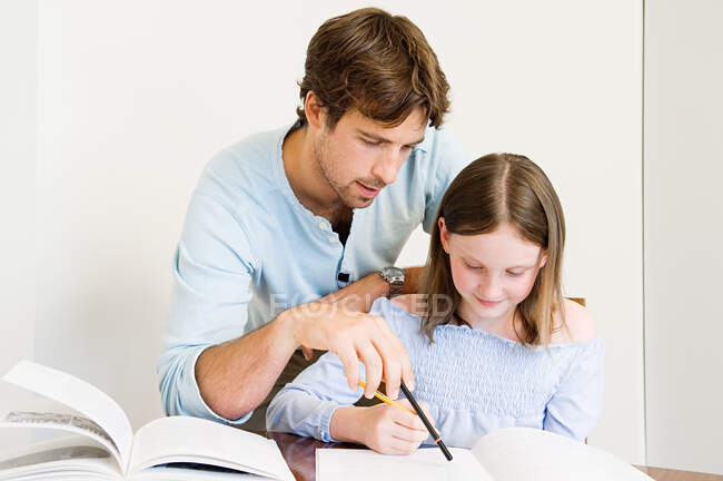 Young man helping daughter with homework — Stock Photo