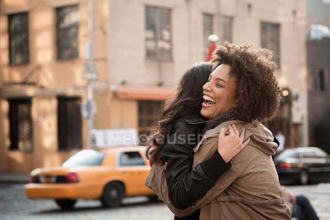 Women hugging on city street — Stock Photo