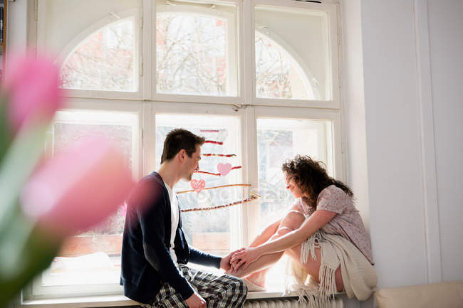 Casal sentado no assento da janela e de mãos dadas — Fotografia de Stock
