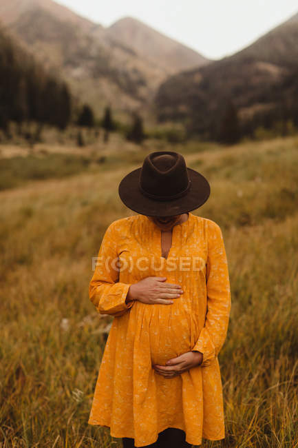 Pregnant woman standing in rural setting, holding stomach,  Mineral King, Sequoia National Park, California, USA — Stock Photo