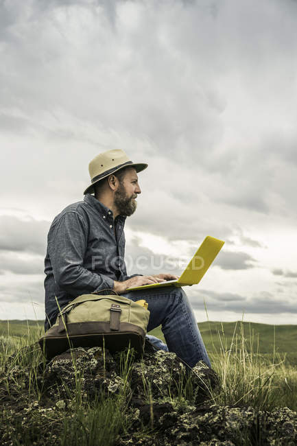 Ältere männliche Wanderer sitzen auf Felsen mit Laptop, cody, wyoming, usa — Stockfoto