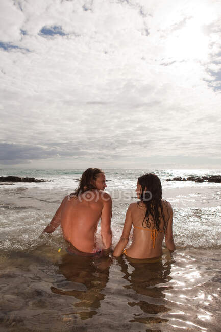 Couple sitting in sea, rear view — Stock Photo