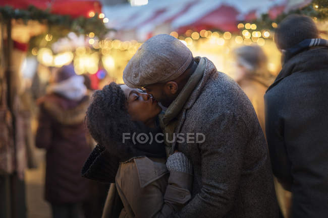 Romántico feliz pareja disfrutando de la ciudad durante las vacaciones de invierno besos en al aire libre mercado - foto de stock