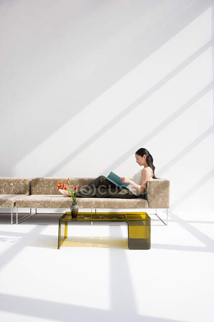 Femme lisant sur un canapé — Photo de stock