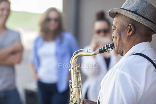 Cape Town, South Africa, man playing saxaphone to crow — Stock Photo