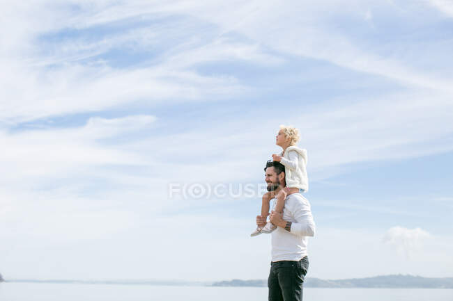 Reifer Mann gibt Tochter an der Küste eine Schultertasche — Stockfoto