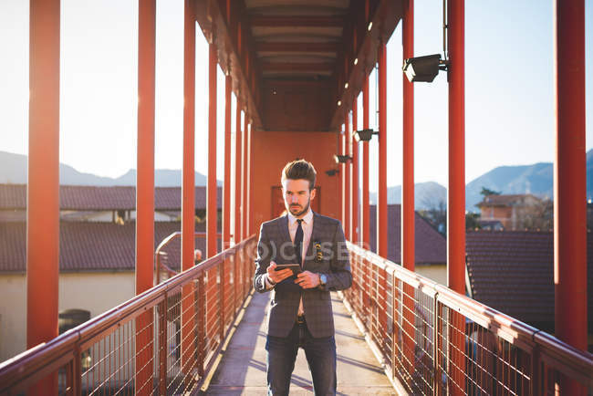 Молодой человек использует цифровой планшет на пешеходном мосту — стоковое фото