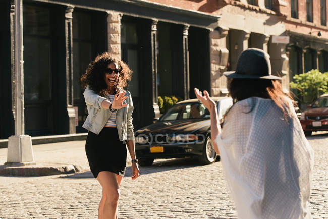 Дві середні дорослі друзі-жінки вітають один одного на міській вулиці — стокове фото