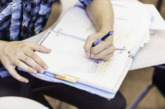 Обрезанный снимок мальчика-подростка, делающего заметки на уроке средней школы — стоковое фото