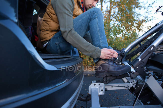 Людина, пов'язуючи шнурок в задній частині автомобіля, користування, Сполучені Штати Америки — стокове фото