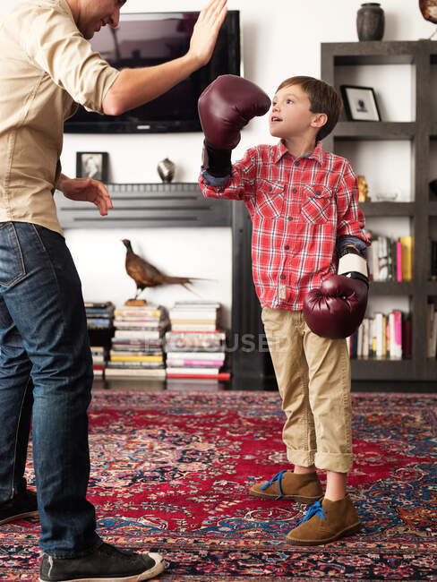 Père enseignant fils à boxer dans le salon — Photo de stock