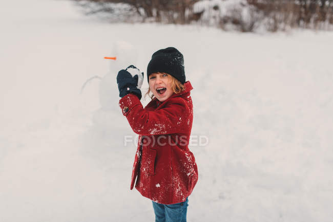 Chica preparándose para lanzar bola de nieve - foto de stock