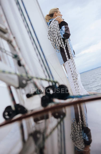 Woman standing on boat, carrying rope on her shoulder — Stock Photo