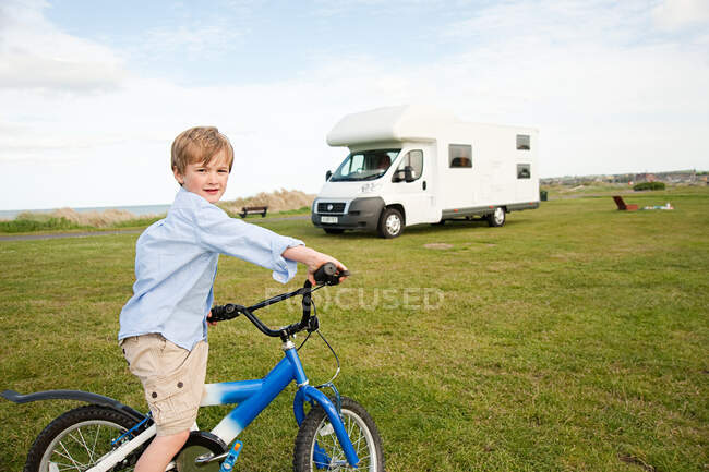 Мальчик с велосипедом возле каравана — стоковое фото
