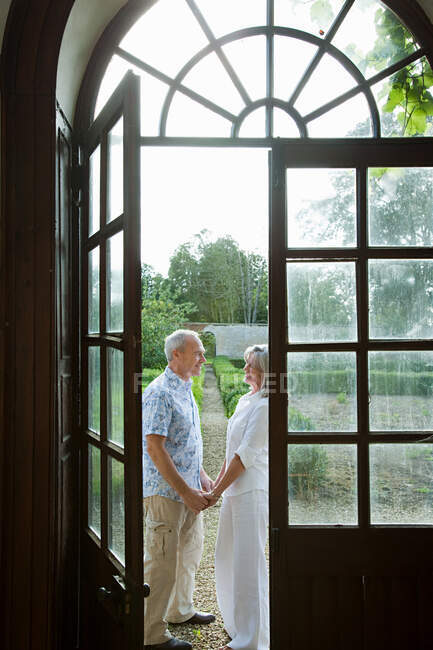 Couple d'âge mûr par des portes françaises — Photo de stock