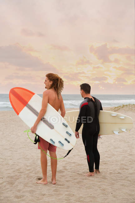 Мужской спасатель и серфер, смотрящий в море с пляжа — стоковое фото