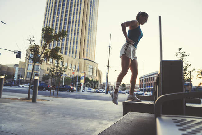 Jeune femme faisant de l'exercice à l'extérieur, s'avançant sur le banc — Photo de stock