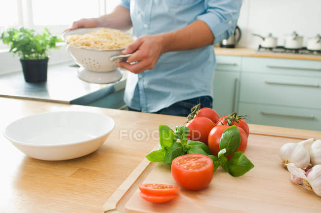 Imagem cortada de homem cozinhar espaguete com tomates — Fotografia de Stock