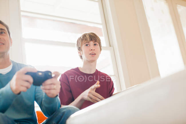 Батько і молодий син грають у відеоігри у вітальні — стокове фото