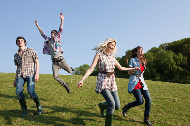 Amigos correndo e pulando ao ar livre — Fotografia de Stock