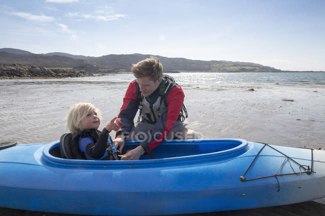Отец помогает сыну в каноэ, Лох-Эйшорт, остров Скай, Гебриды, Шотландия — стоковое фото