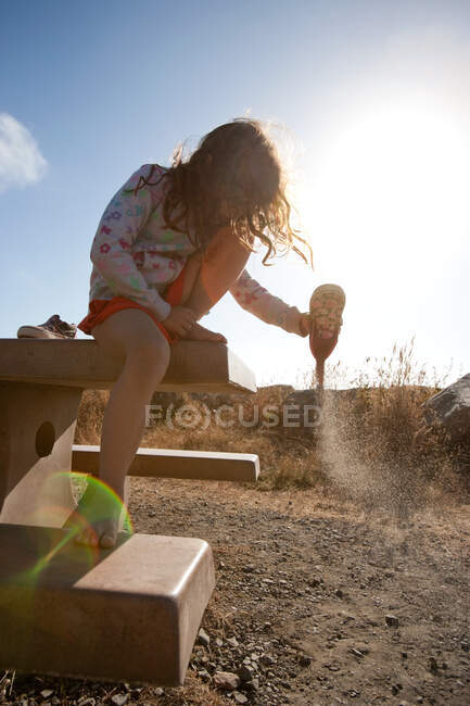 Menina esvaziar areia do sapato — Fotografia de Stock