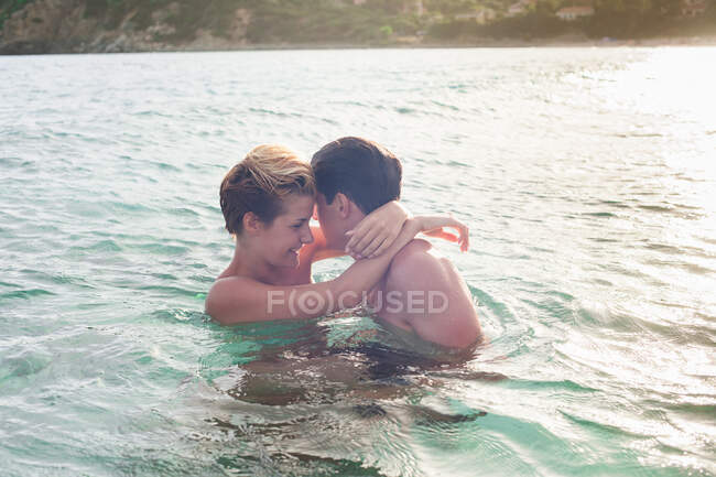 Улыбающаяся пара, обнимающаяся в воде — стоковое фото
