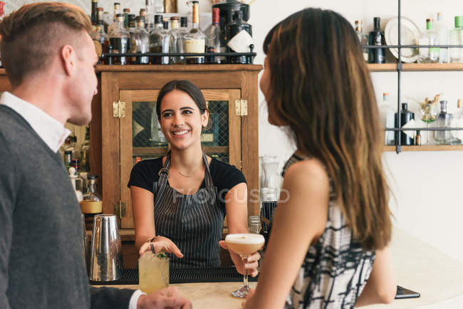 Camarera sirviendo pareja joven en bar de cócteles - foto de stock