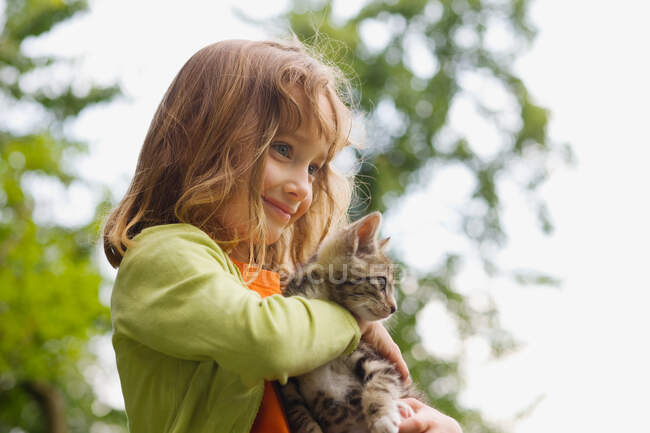 Una chica sosteniendo un gatito - foto de stock