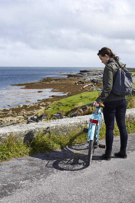 Молода жінка стоїть біля морського муру (Інішмор, Ірландія). — стокове фото