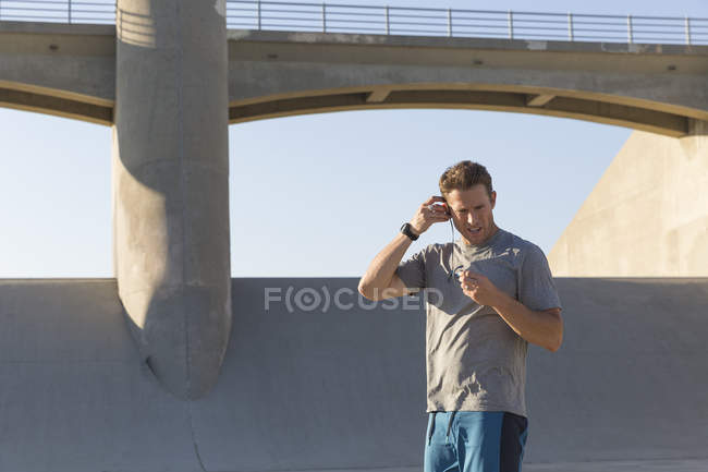 Männlicher Athlet setzt Kopfhörer auf, van nuys, Kalifornien, USA — Stockfoto