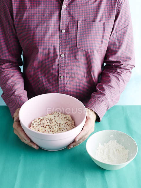 Man wearing purple shirt holding bowl of dough — Stock Photo