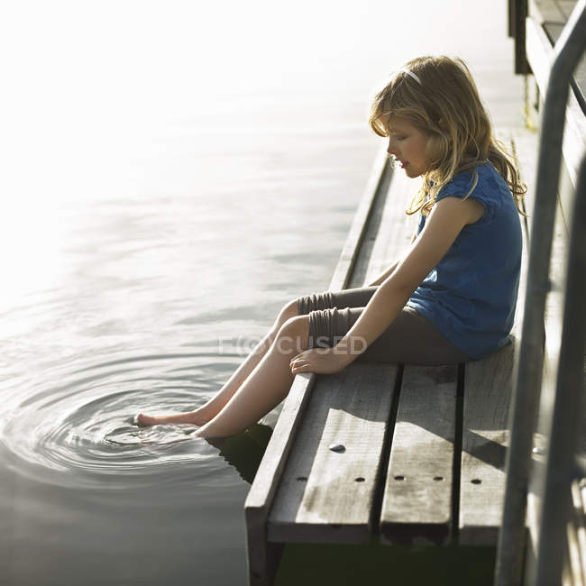 Girl dipping feet in lake — Stock Photo