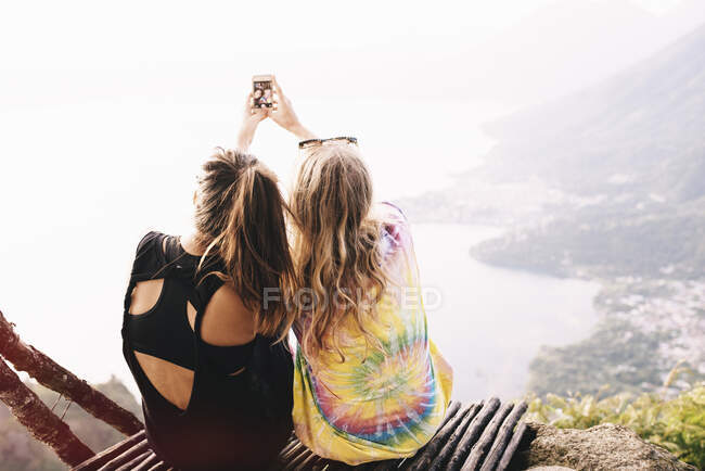 Vue arrière de deux amies prenant selfie smartphone au lac Atitlan, Guatemala — Photo de stock