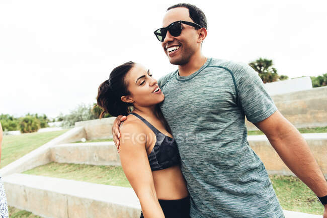 Young man and woman wearing sports clothing, outdoors, hugging, South Point Park, Miami Beach, Florida, USA — Stock Photo