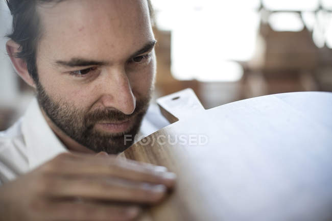 Close up of man inspecting chopping board in factory — Stock Photo