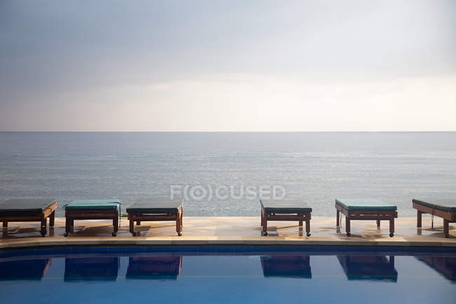 Шезлонги біля басейну з видом на океан — стокове фото